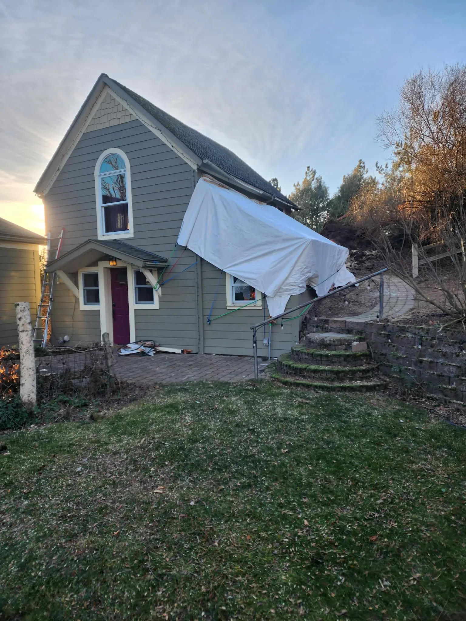 Residential home with white protective sheeting covering tree removal work area