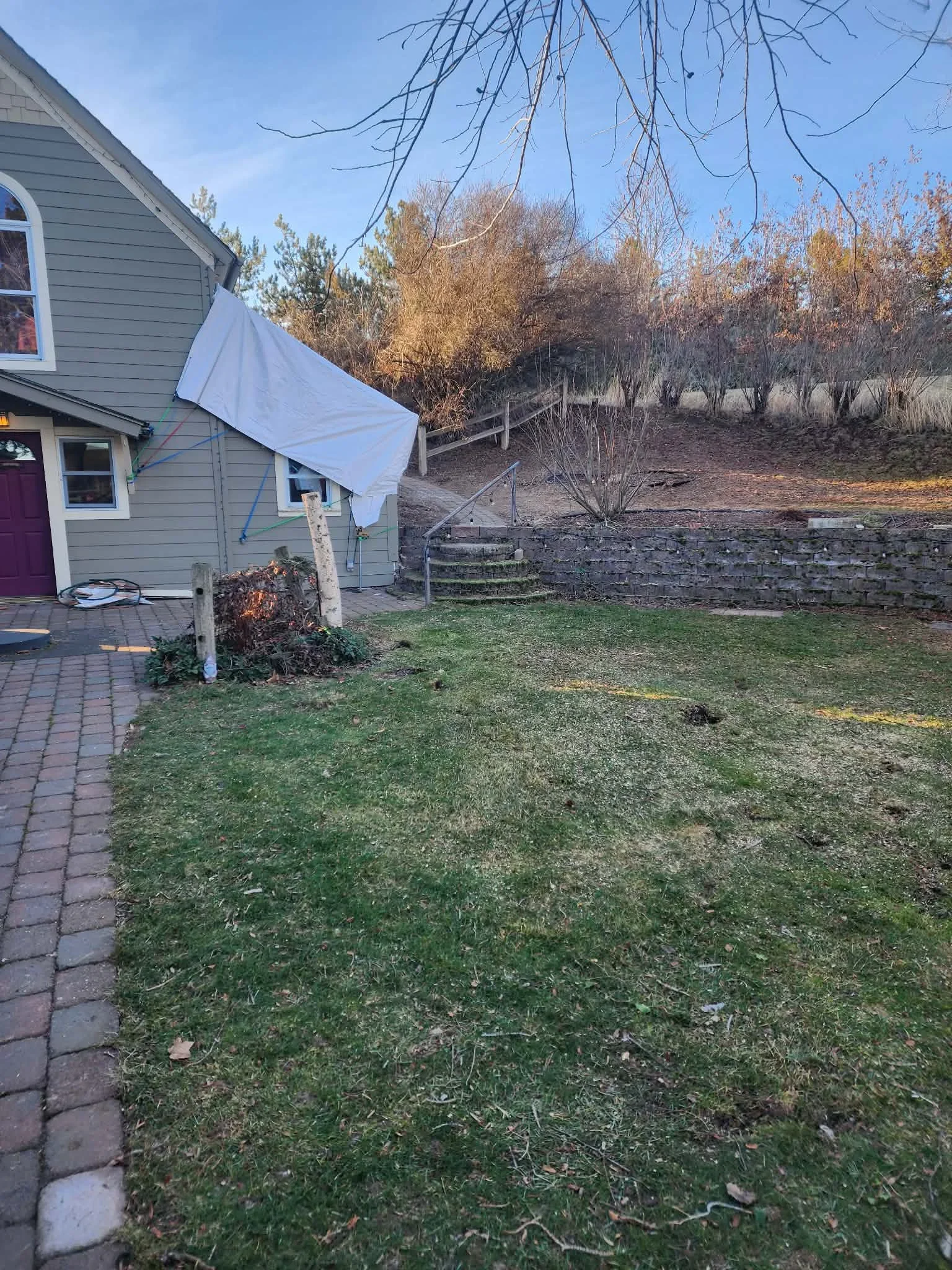 Cleared residential yard with stone retaining wall, removed tree debris, and manicured lawn